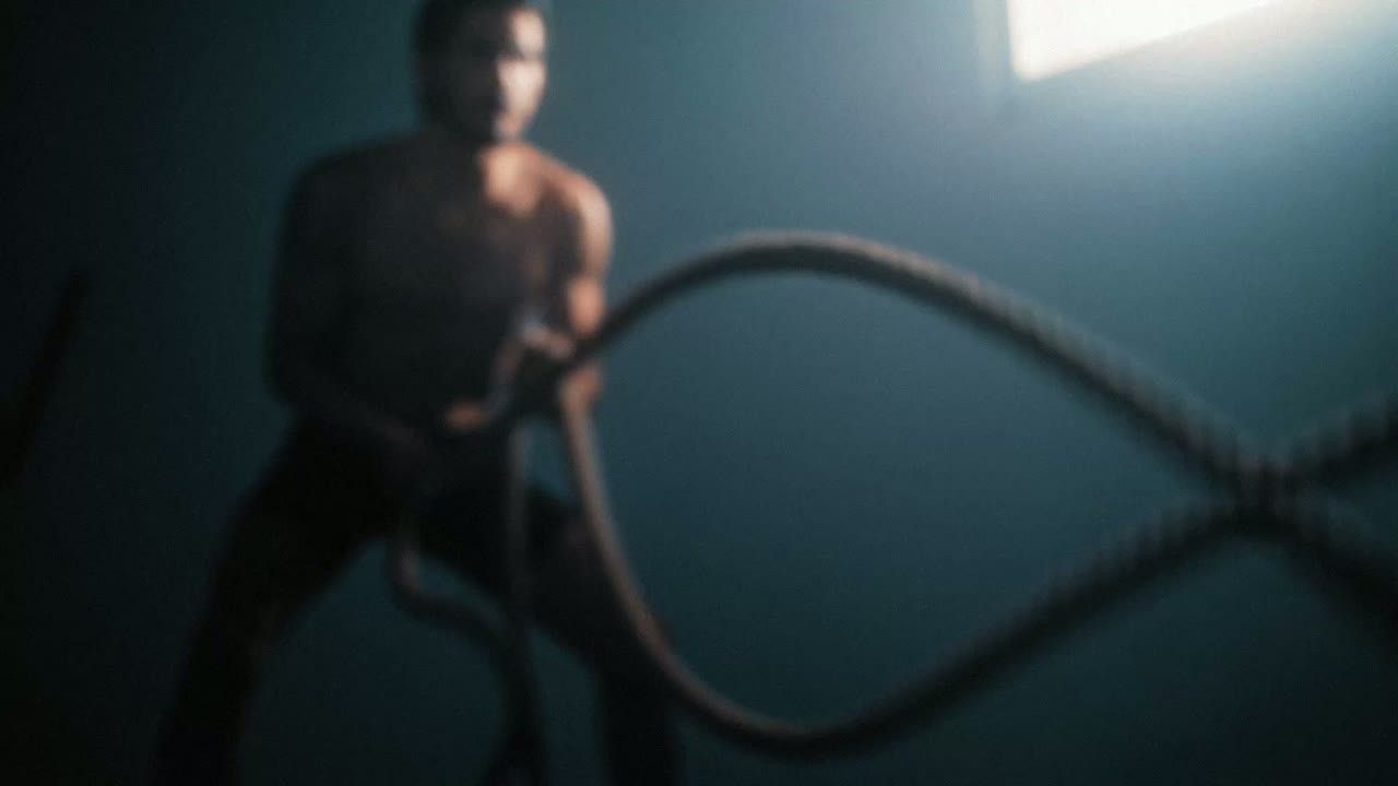 Man training with battle ropes in a dim gym
